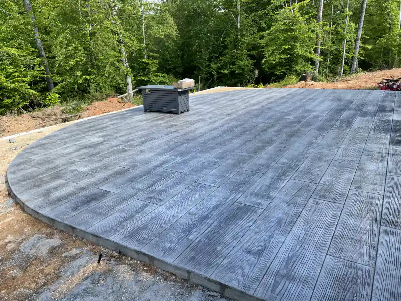 Stamped concrete finished to imitate wood planking, with grain texture and plank joints.
