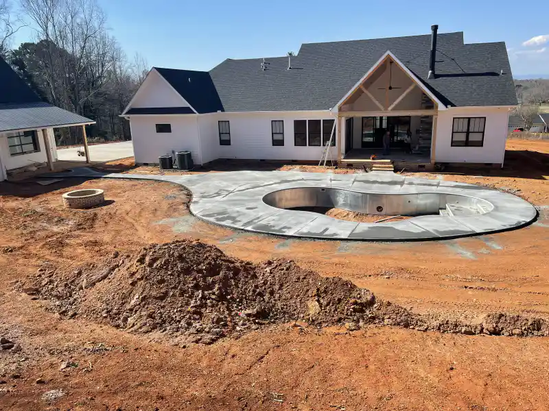 A concrete pool deck beside an in-ground swimming pool.
